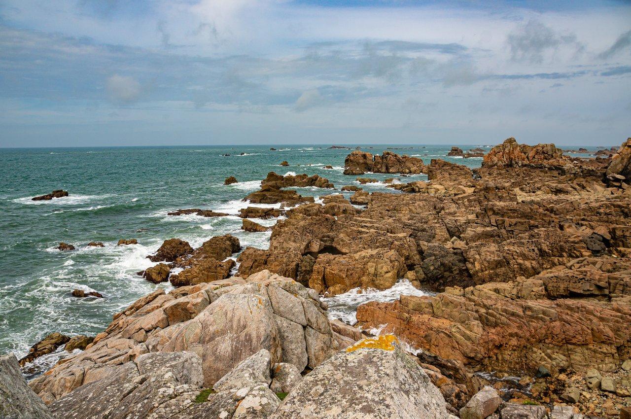 Paysage côtier breton, mêlant falaises, forêts et ciel clair, révèle la beauté sauvage de la Bretagne.