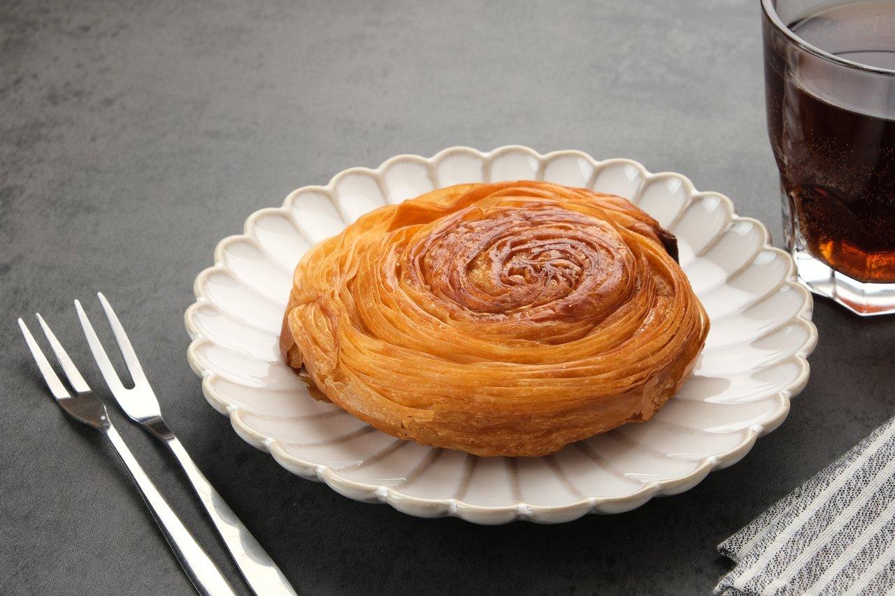 Un golden Kouign-Amann dessert, doré avec un caramel léger, accompagné d'une boule de glace vanille.